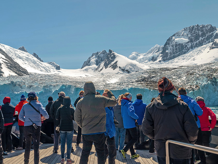 A group on the deck of Scenic Eclipse in front of a galcier