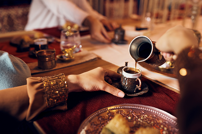 A person pouring traditional Arabic Coffee into a mug.