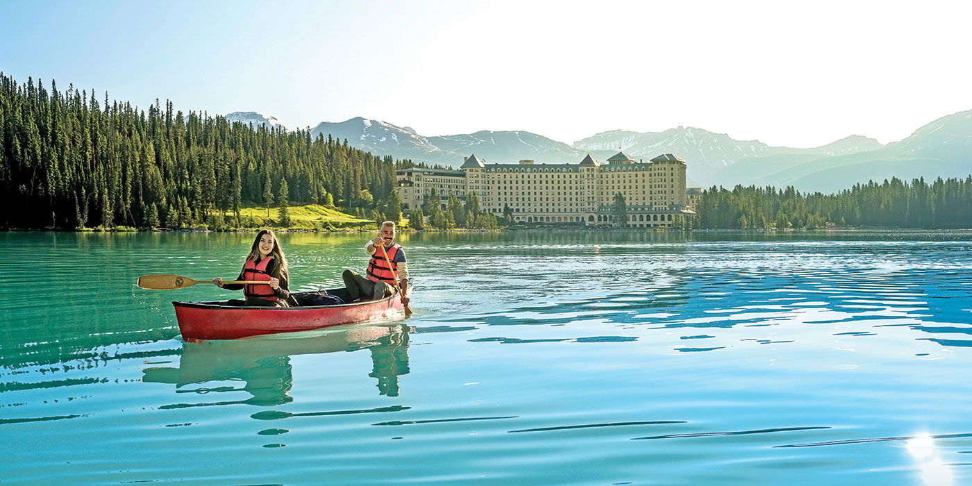 A man and woman canoeing on Lake Louise in Canada on a sunny day. 