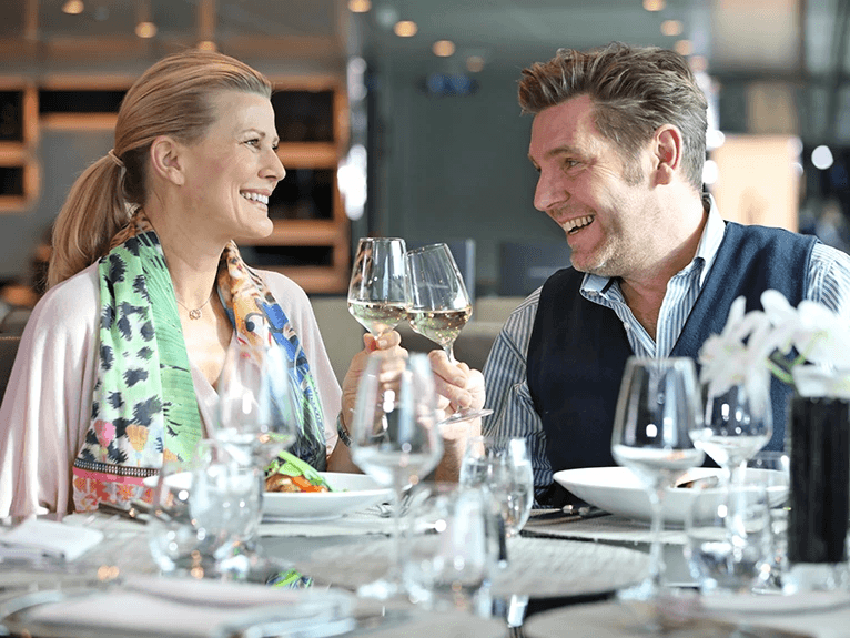 A man and woman having a glass of wine and a meal at Crystal Dining on a Scenic Space-Ship in Budapest
