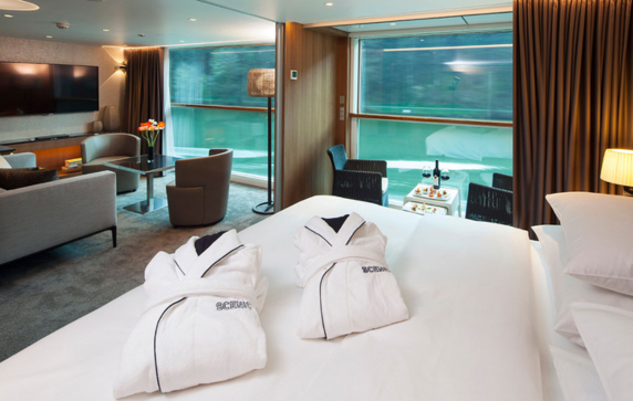  The luxurious lounge area and queen bed in the Royal Balcony Suite on the Scenic Amber ship. 