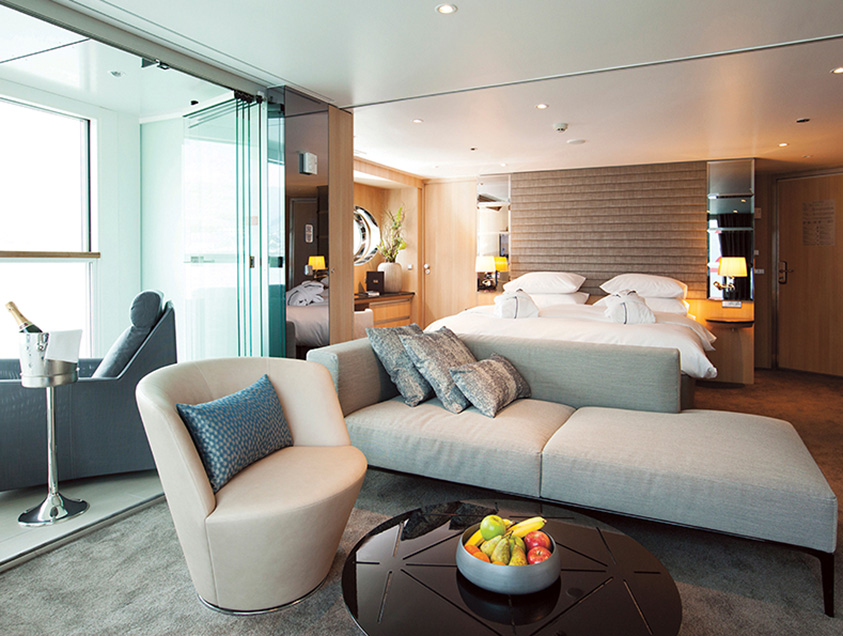 Queen bed and comfortable lounge area in a Royal Panorama Suite on the Scenic Jasper cruise ship Image