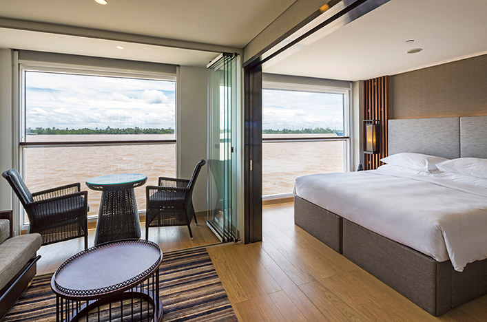 Deluxe Suite with floor-to-ceiling windows providing a view of the surrounding river, Scenic Spirit 