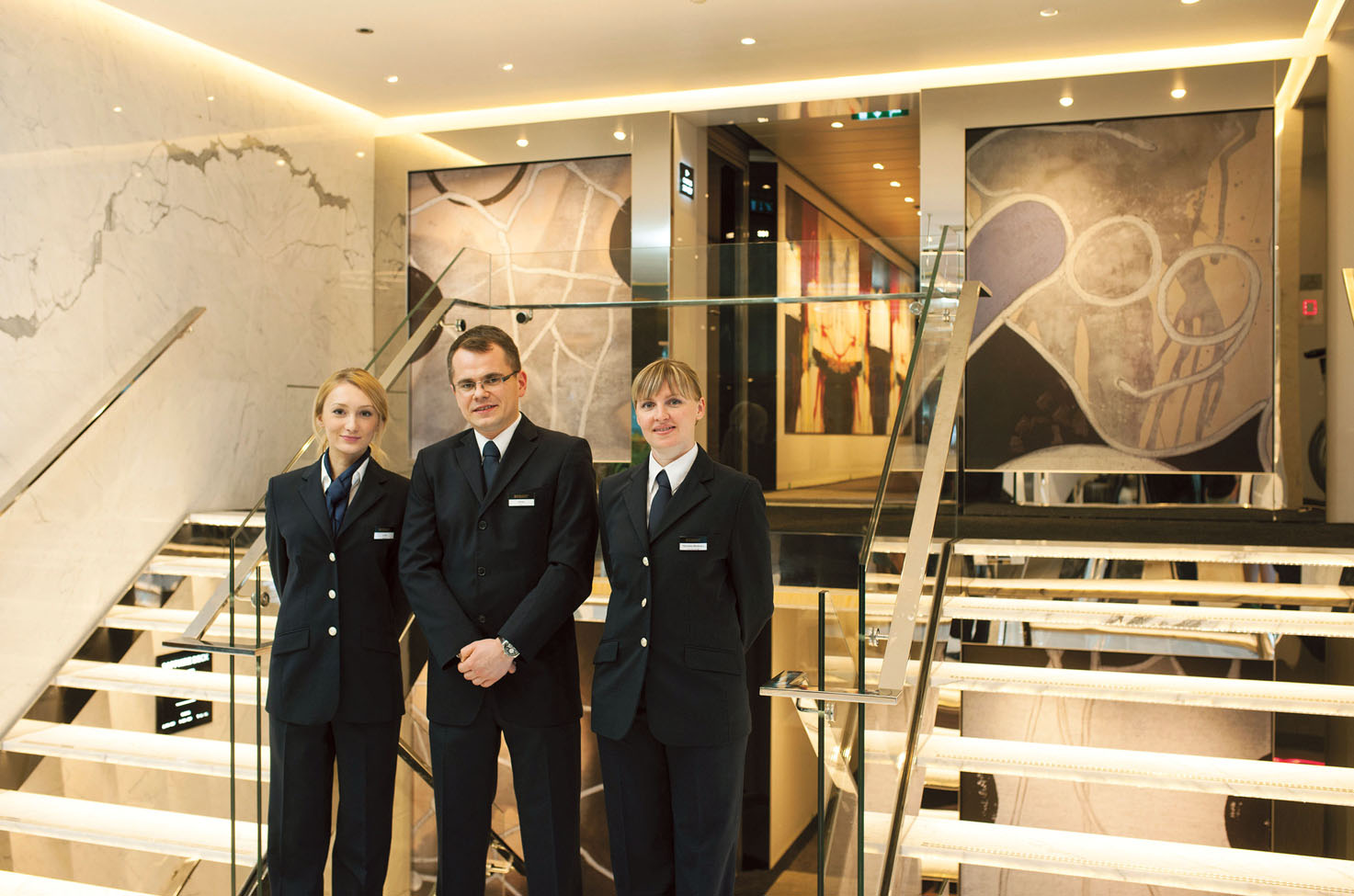Three members of crew stand by a white and silver staircase