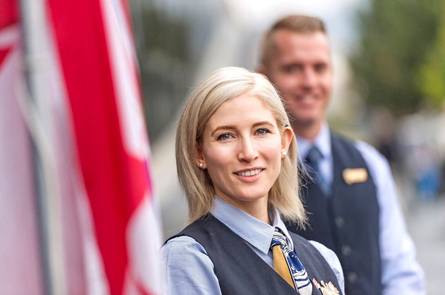 a woman and a man dressed in blue shirts and waitcoats who are members of staff from The Rocky Mountineer